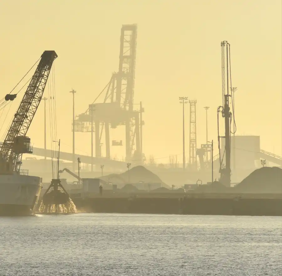Un homme sur le port, face à une dragueuse sortant la drague de l'eau. Un paysage brumeux au lever du jour. 11° Lauréat du concours photo WinSPOT by Data Concept