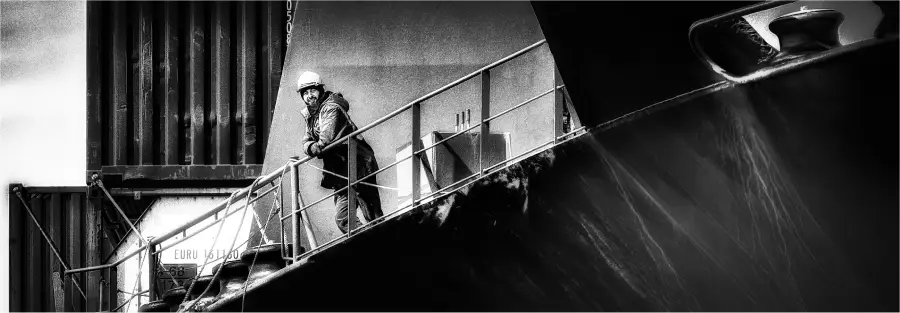 Un homme seul sur le pont d'un bateau, souriant et en pleine réflexion. 14° Lauréat du concours photo WinSPOT by Data Concept