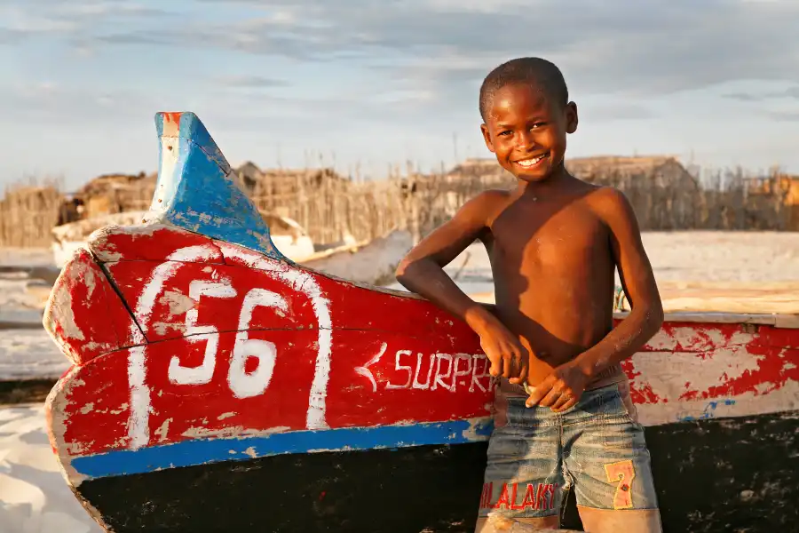 Un enfant souriant devant une pirogue. un paysage d'Afrique 18° Lauréat du concours photo WinSPOT by Data Concept
